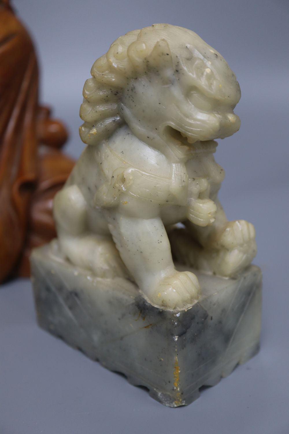 A Japanese rootwood carving of a seated elder, inset eyes and teeth and a pair of Chinese soapstone shishi, each crouched on a rectangu